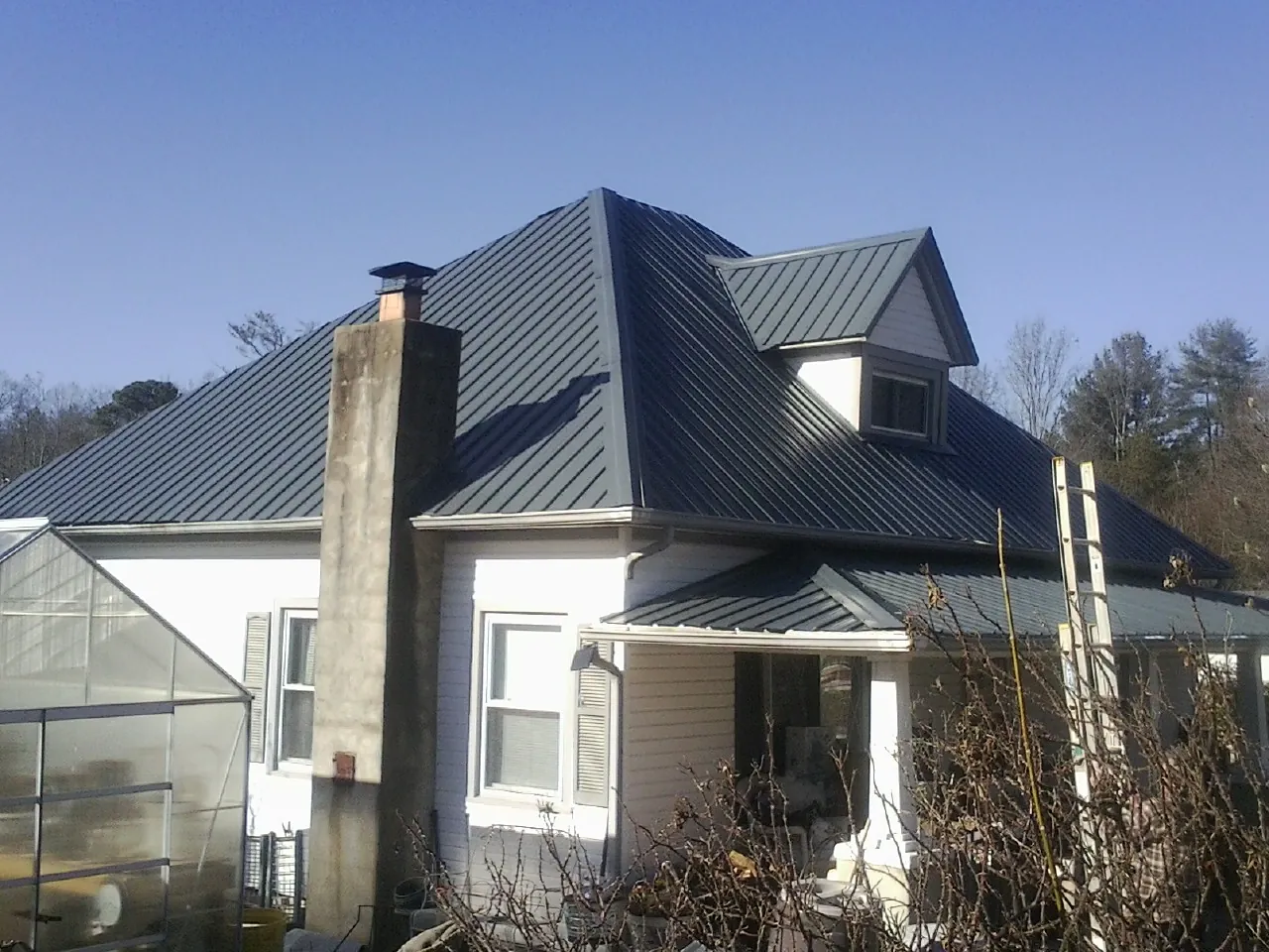 Dark blue standing seam metal roof on a white farmhouse with dormer — Slate & Tile Roof Repair by Roofing Brothers in Azle