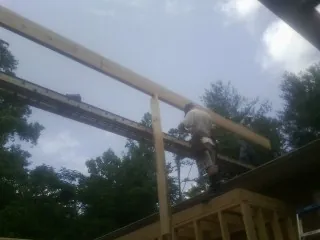 Carpenter setting a ridge beam over a new addition frame — Ice Dam Removal by Roofing Brothers in Azle