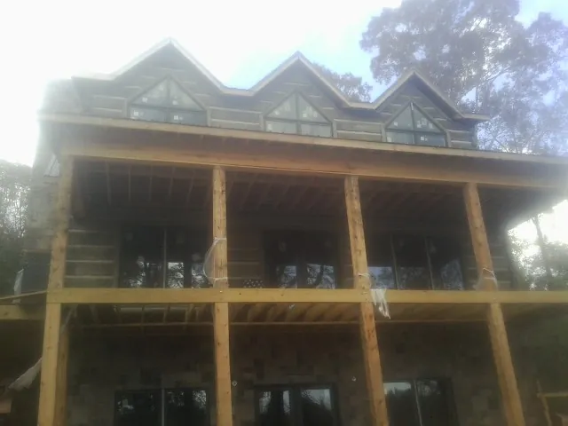 Dormers and porch framing on a large log home under construction — Roof Coating work by our crew in Azle