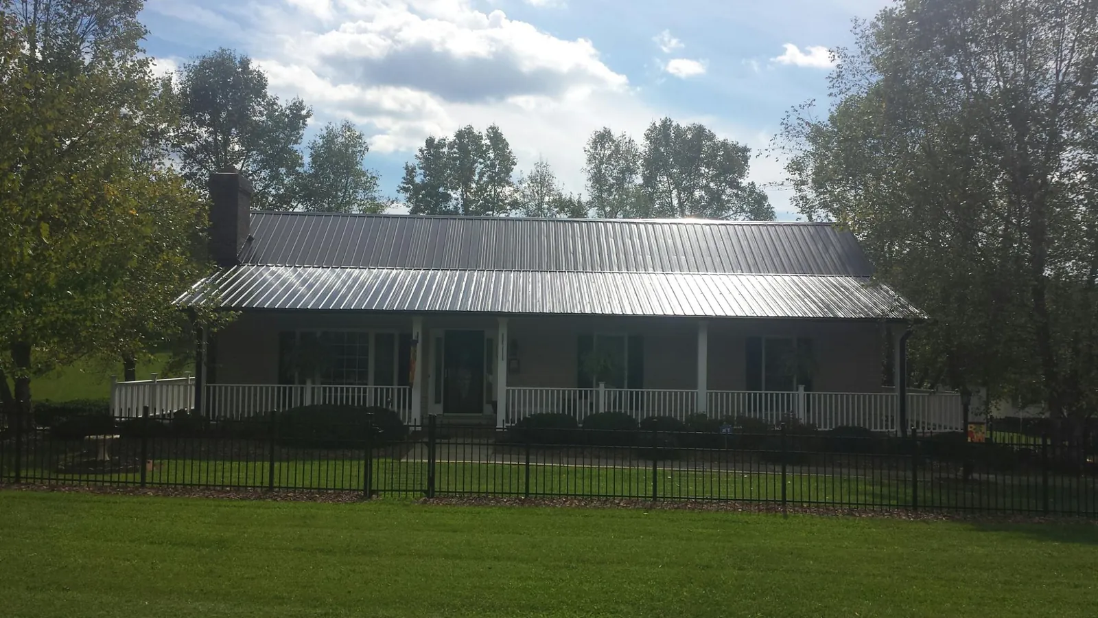 Gray metal roof on a brick ranch with a full width front porch — Gutter Guard Installation work by our crew in Azle