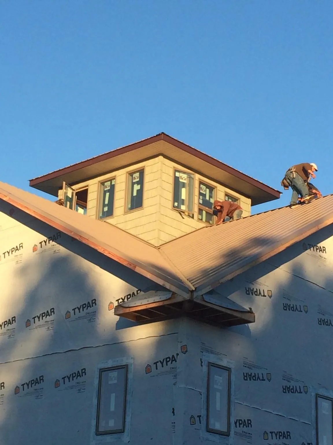 Roofers working around a rooftop cupola on a new metal roof at sunset — Roof Waterproofing in Azle by Roofing Brothers